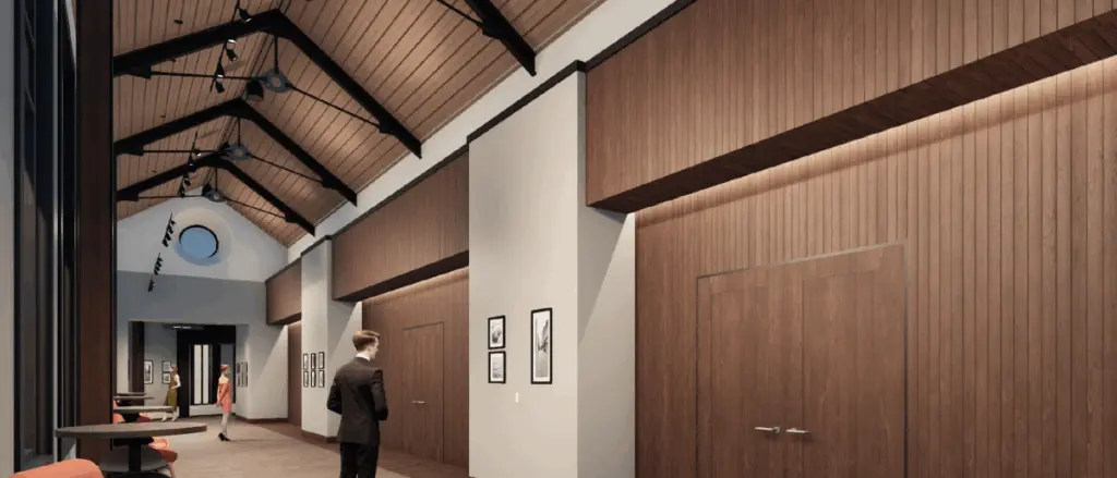 A modern hallway in Building and Spaces style features vaulted wood ceilings, wood-paneled walls, and framed art. Two people are walking inside; one man in a suit is in the foreground, and a woman in a dress is further down the hall.