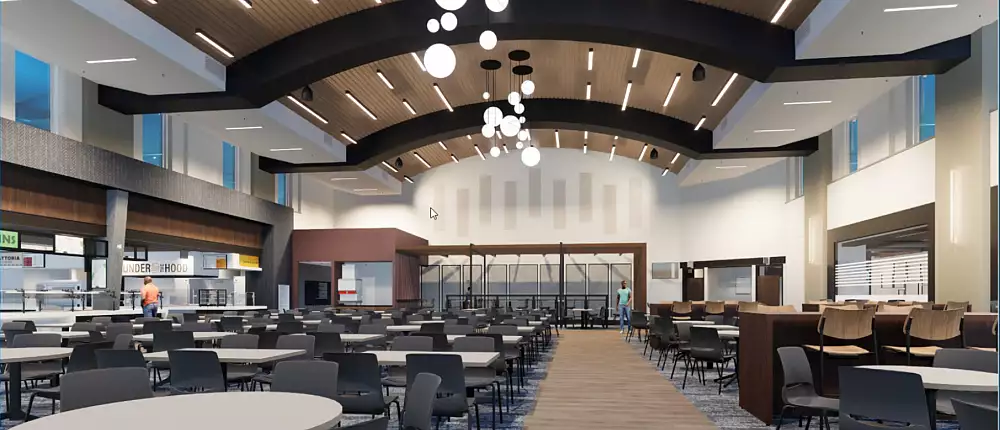 A spacious, modern dining hall in Building and Spaces features round tables and chairs, high arched ceilings, contemporary light fixtures, and floor-to-ceiling windows providing natural light. A food service area is visible on the left.